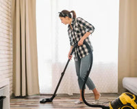 Woman using a central vacuum system to clean hardwood floor in a modern living room